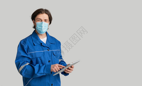 年轻的数量测员戴着医用口罩并使用数字平板电脑图片