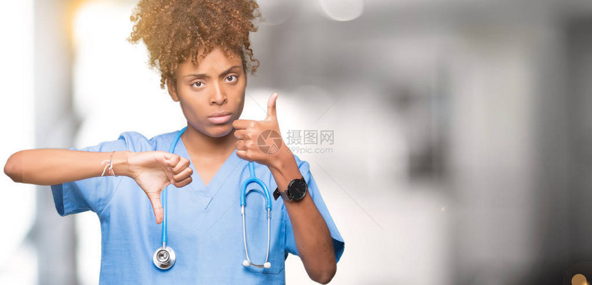身处孤立背景的年轻非洲女医生在上下伸起拇指不同意见和协议表达中表现不一图片