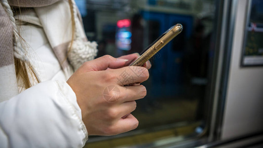 亚洲旅游女人在地铁里拿着智能手机乘客在地铁中使用技术电话通讯方式图片