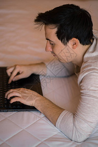 在酒店房间或家庭卧室使用笔记本电脑的人图片