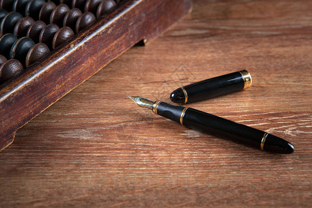 桌子上的钢笔与算盘特写高清图片