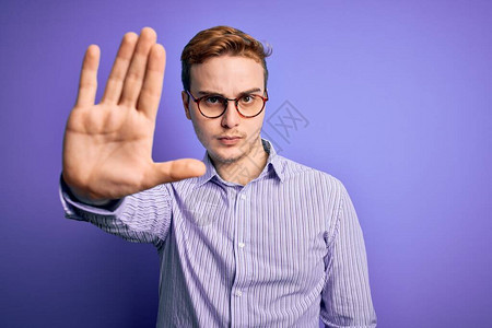 身穿轻便衬衫和紫底眼镜的英俊红发年轻男子用手掌停止歌唱图片