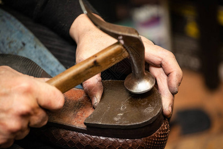 男鞋匠通过钉鞋跟修鞋的手特写图片