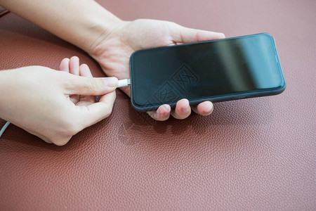 妇女用手机智能手机在沙发上用手充电图片