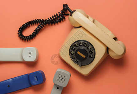 热线办公室概念旧旋转式电话许多关于珊瑚颜色背景的听筒顶视图片