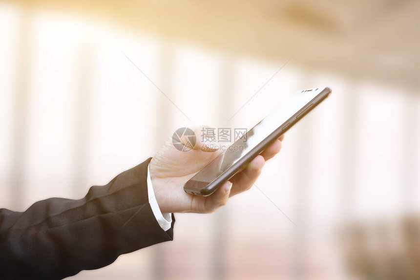 使用移动智能手机对商人的手进行近距离检查图片