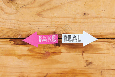 虚假或真实的概念假的或真实的写在木制背景上的纸箭背景图片