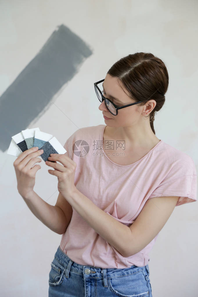 年轻女子在她新家的墙壁上选择完图片