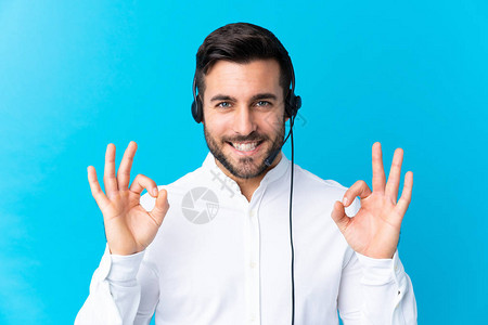 电讯推销员用耳机在孤立的蓝色背景下工作图片