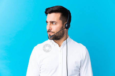 电讯推销员用耳机为孤立的蓝底背景戴耳机图片