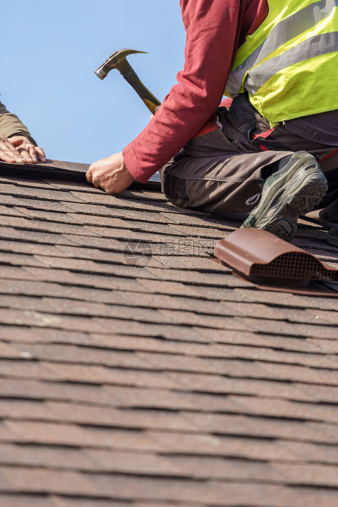建设中的建设理念两名身穿工作服手戴头盔在新房顶安装屋顶瓦片的职业工图片