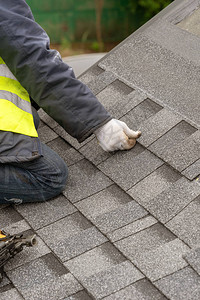 在建房屋顶上安装沥青或沥青瓦的特殊防护工作服和发光专业屋顶工人的垂背景图片