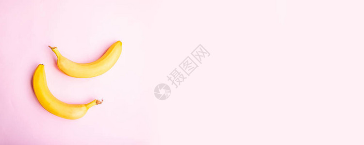 粉红色背景上甜两个香蕉的平面组合图片