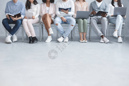 坐在排队等待工作面试持有笔记本电脑平板电脑书本广告空间的临图片