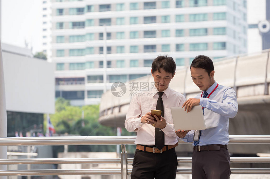 两位商人正在用智能手机和笔记本做商业概念图片