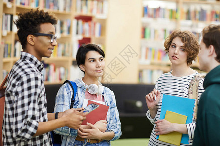一群内容沉思的多民族青年大学生站在现代图书馆区图片