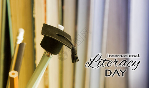 国际扫盲日概念与书本背景上铅笔上的研究生帽图片