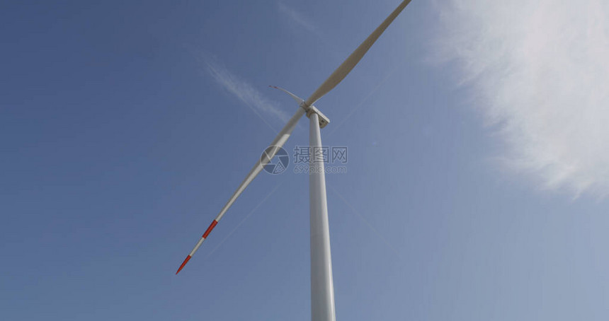 向农村发电站现代风力涡轮机行进的一组工程师倾斜图片