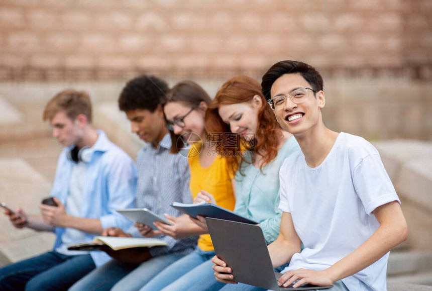 亚洲学生与坐在大学楼外的同学一起学习学生活理念图片