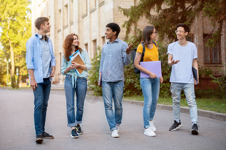 一群多元文化的一年级学生在外面的大学楼附近散步图片