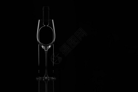黑色背景上的优雅酒杯和酒瓶玻璃后面的瓶子轮廓水平的复制空间您的文本图片