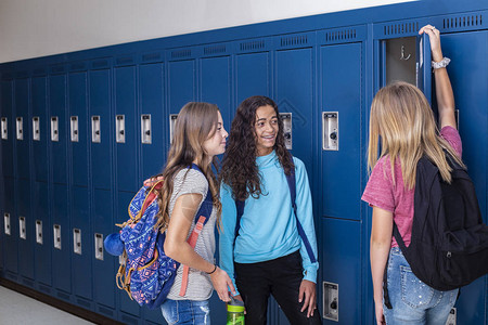 三个初中生在学校走廊里一起交谈的坦率照片不同的女学生在学校休息时一图片