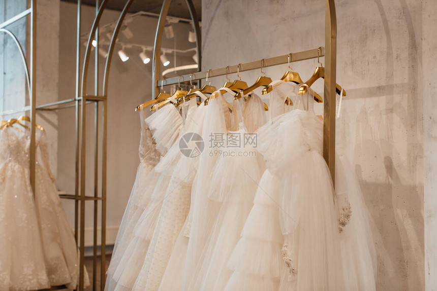 漂亮的白色婚纱挂在商店的衣架上图片