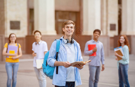 大学生快乐的千禧一代站在大学楼附近的多民族学生中图片