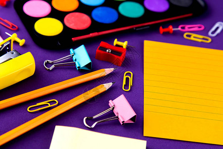 学校办公室文具放在紫色背景桌子上图片