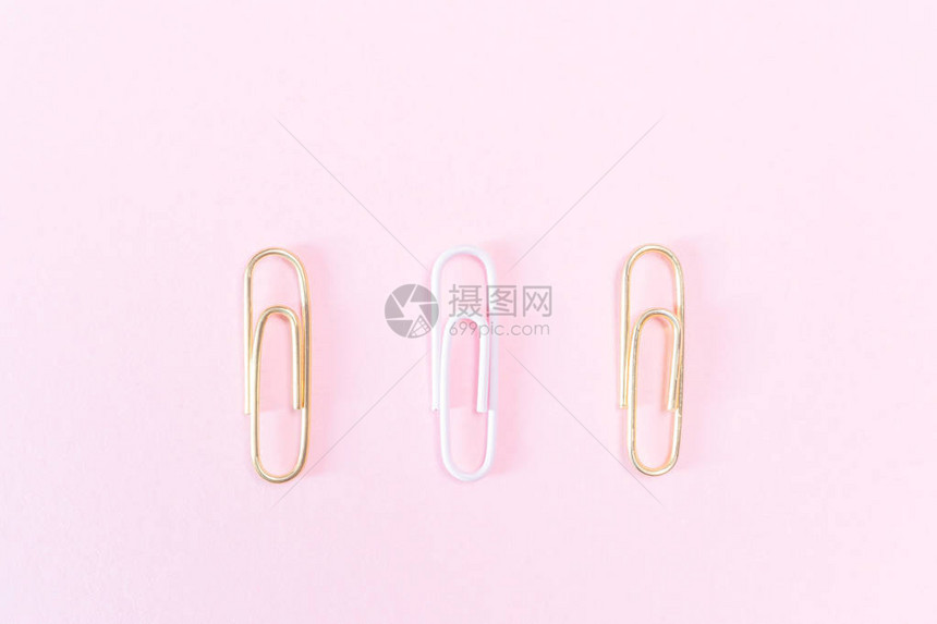 柔和的粉红色背景上的粉红色和金色回形针文具学习办公商务的概图片