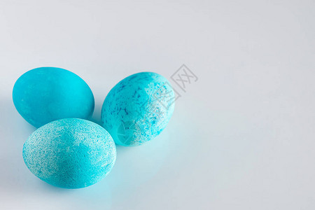浅色背景上的三个蓝色复活节彩蛋三个美丽的蓝色复活节彩蛋特写在白色背景上背景图片