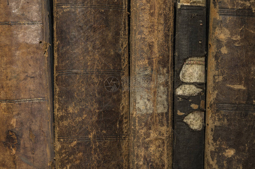 在图书馆或博物馆的木质表面上堆放着一堆旧的老式的古籍的书籍温暖的定向光图片