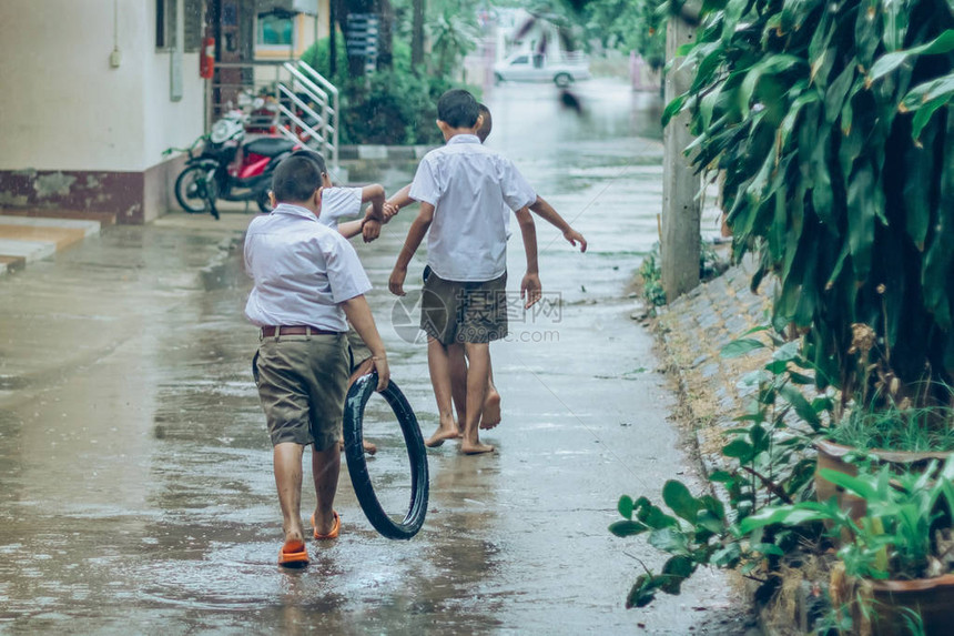 男孩学生在学校暴雨后离开教室在街上散步图片