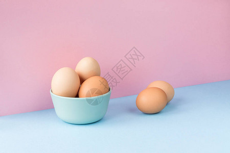 在浅蓝色和粉色背景的碗里几个棕蛋的最小图像复图片