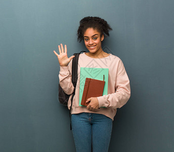 年轻的黑人女学生展示了第五名她拿着书图片