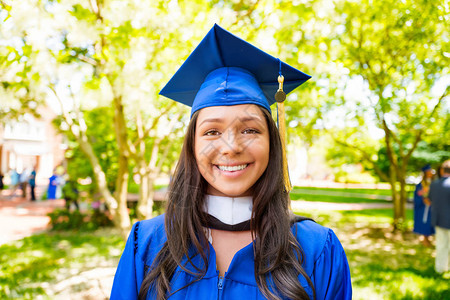 穿着帽子和礼服的年轻女大学生在大学花图片