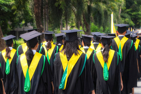 一群身穿黑色长袍的大学毕业生的后视图在大学毕业典礼上排队等候学位图片