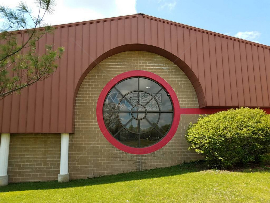 砖砌建筑上有黄蜂巢的大型反光圆形玻璃窗图片