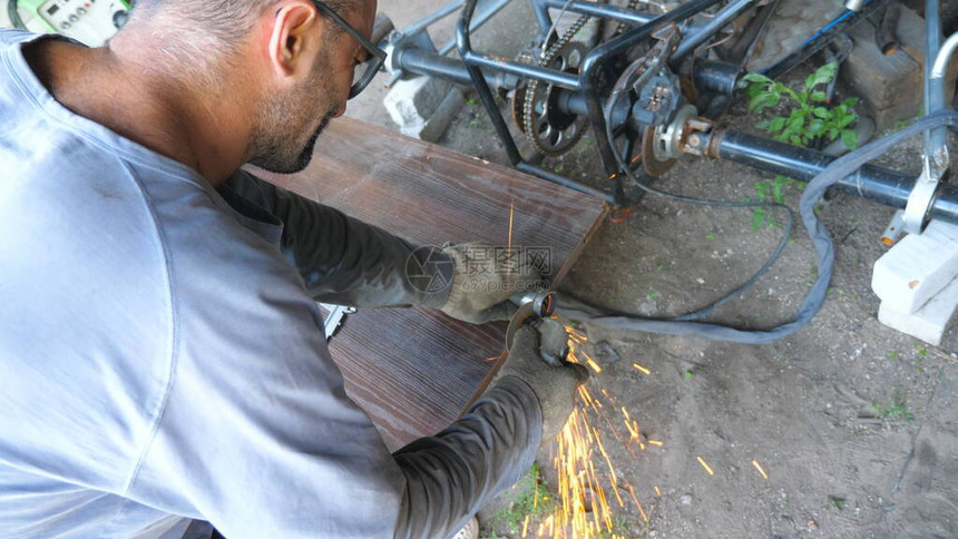 成人修理工或机械师使用圆锯研磨金属工人在车库或车间切割一些细节男子用电动砂轮锯铁零件慢动作图片