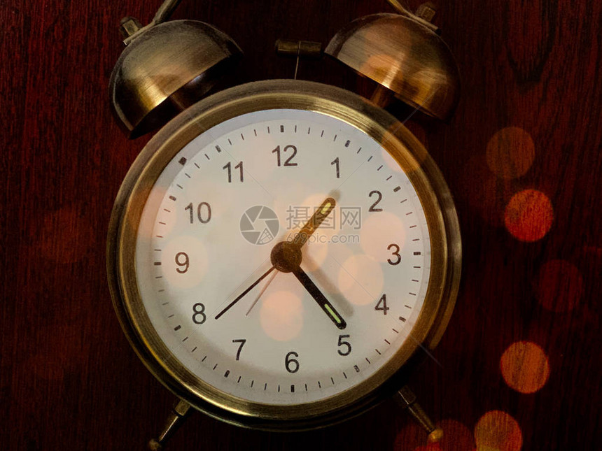 深色背景上的老式闹钟多色灯光下的圆形时钟带有数字和箭头的桌面机械时钟概图片