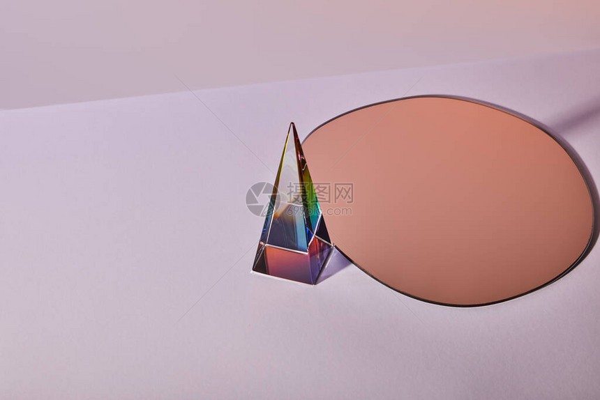 紫色背景上的水晶透明金字塔和圆形镜子图片
