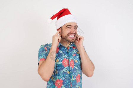 穿着圣诞老人帽子的年轻人用手指把耳朵遮起来图片