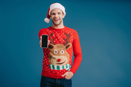 穿着圣塔帽和圣诞节毛衣的帅男子显示智能手机图片