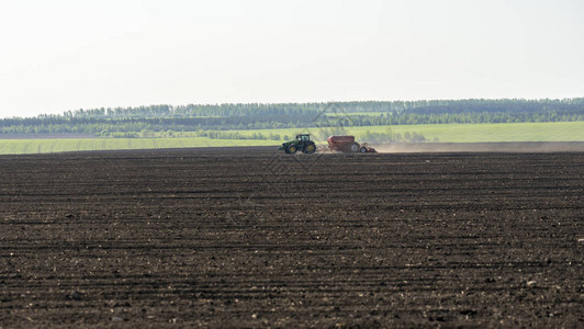春季田间工作拖拉机在绿地背景下图片