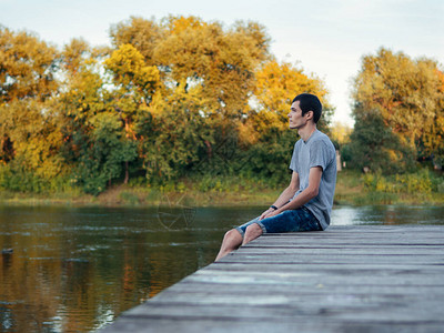 青少年坐在户外河边的木桥上图片