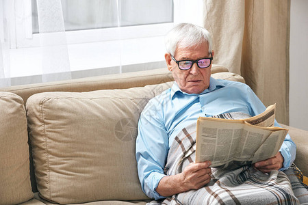 穿着格子阅读报纸的高级灰色头发男子图片