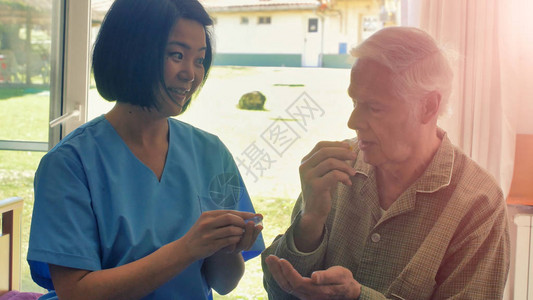 年轻的亚洲女医生帮助老年退休男子在病图片