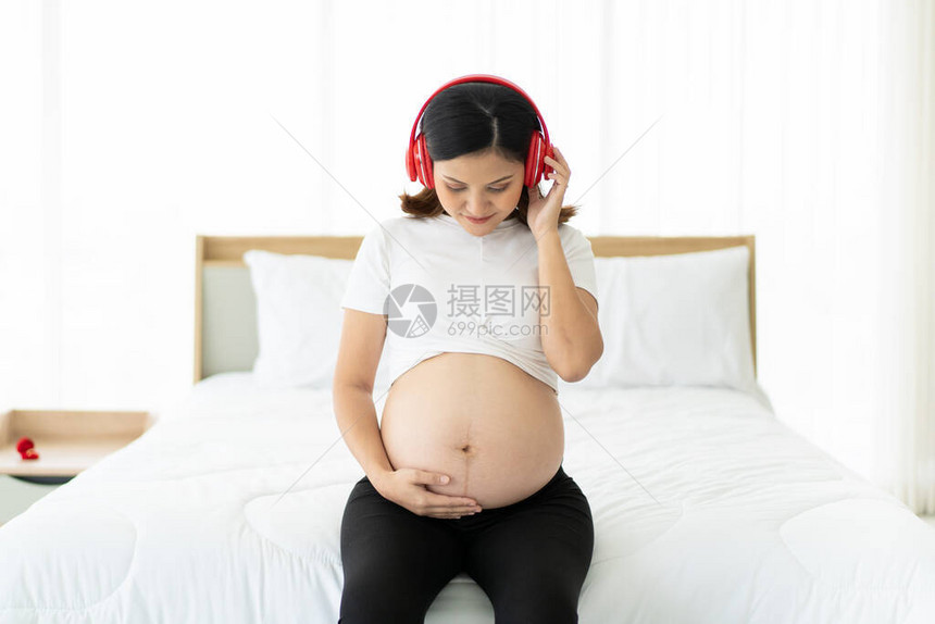 快乐的孕妇在她的卧室里放松图片