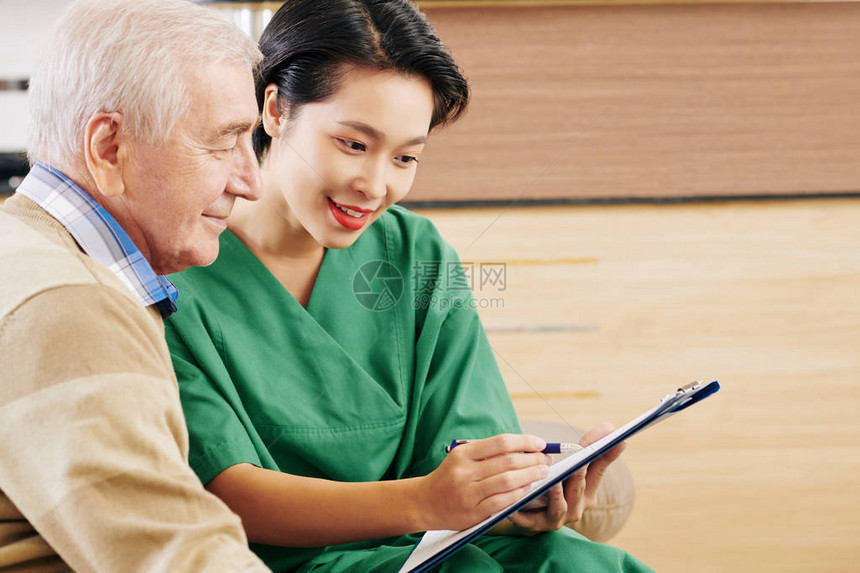 年轻的越南养老院志愿者展示老人的体检结果并解图片