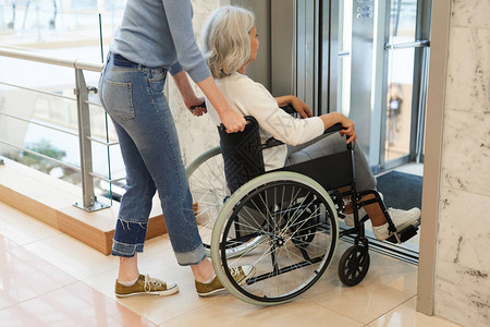在轮椅移动电梯中帮助老年残疾病人的年图片